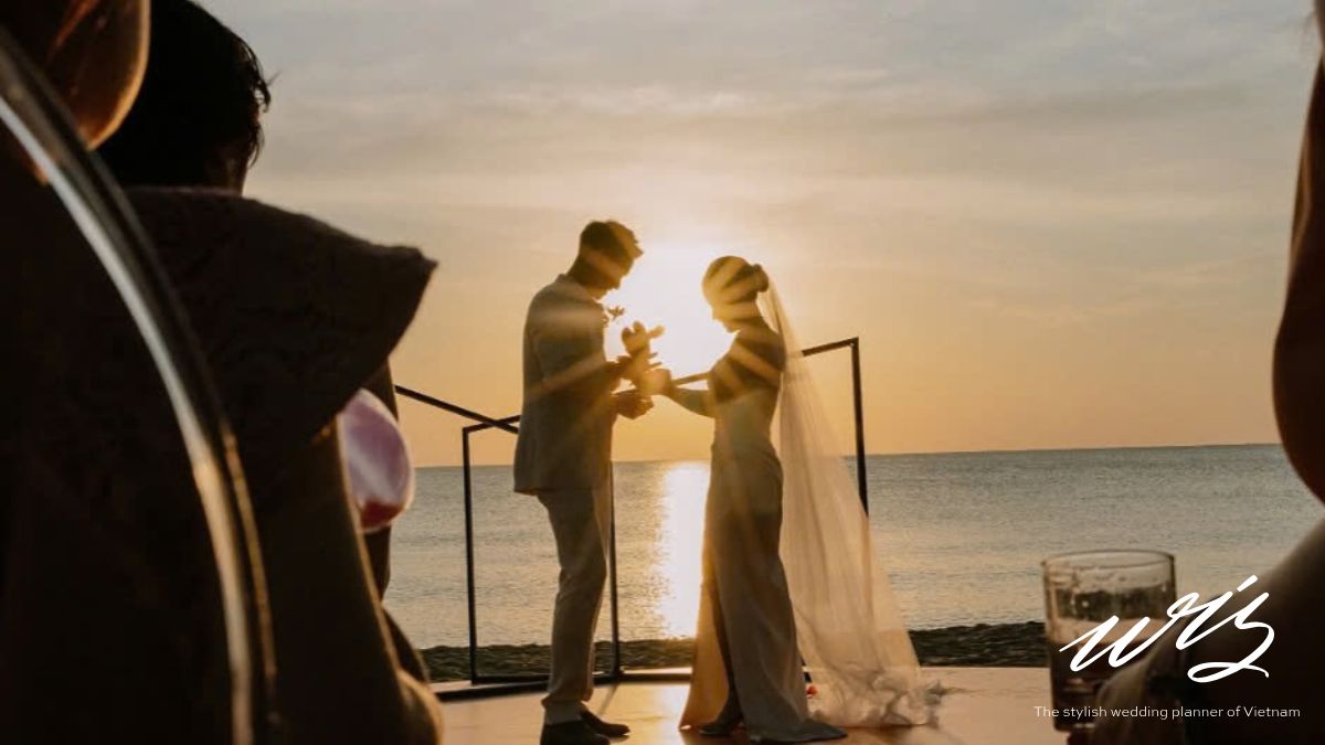A bride and groom exchanging vows during a beach sunset ceremony in Phu Quoc, factoring into the vietnam destination wedding cost